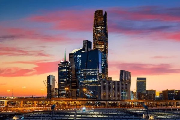 Skyline view of Riyadh, Saudi Arabia, at sunset, showcasing modern skyscrapers and city lights.